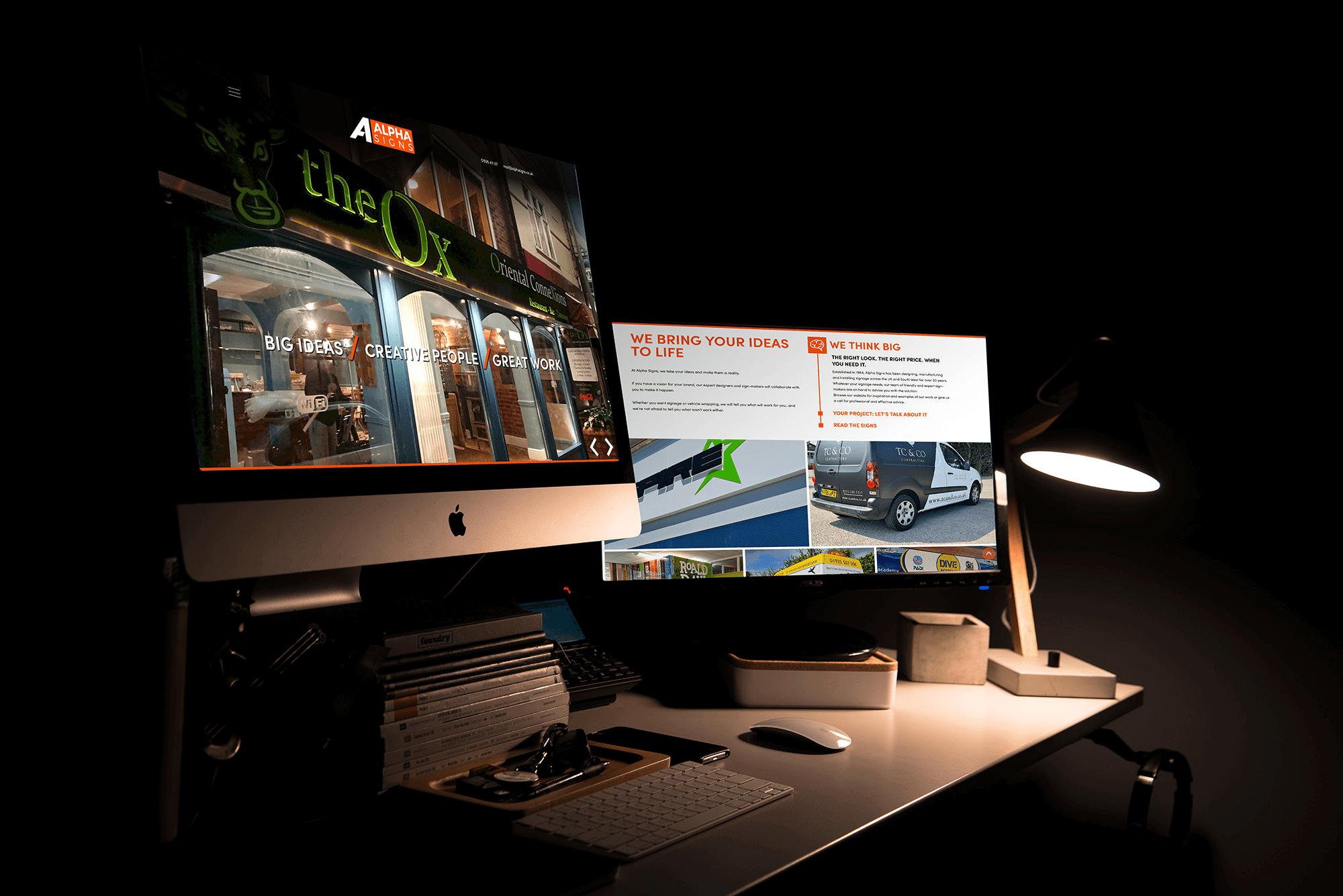 Desk setup showing iMac displaying website for The Lox, with printed marketing materials and design mockups alongside.