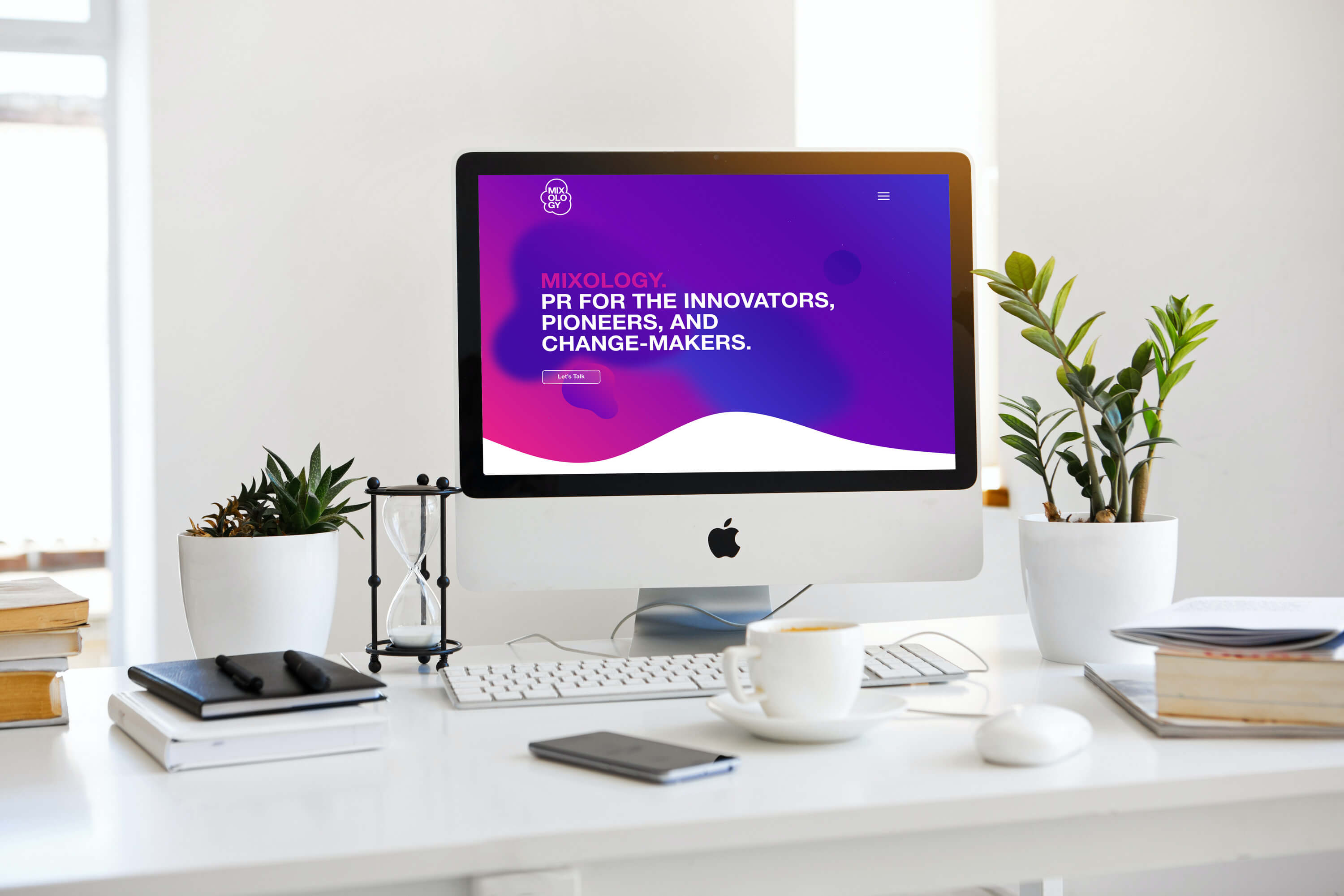Apple iMac displaying purple website design with "Mixology PR" headline on bright workspace desk.