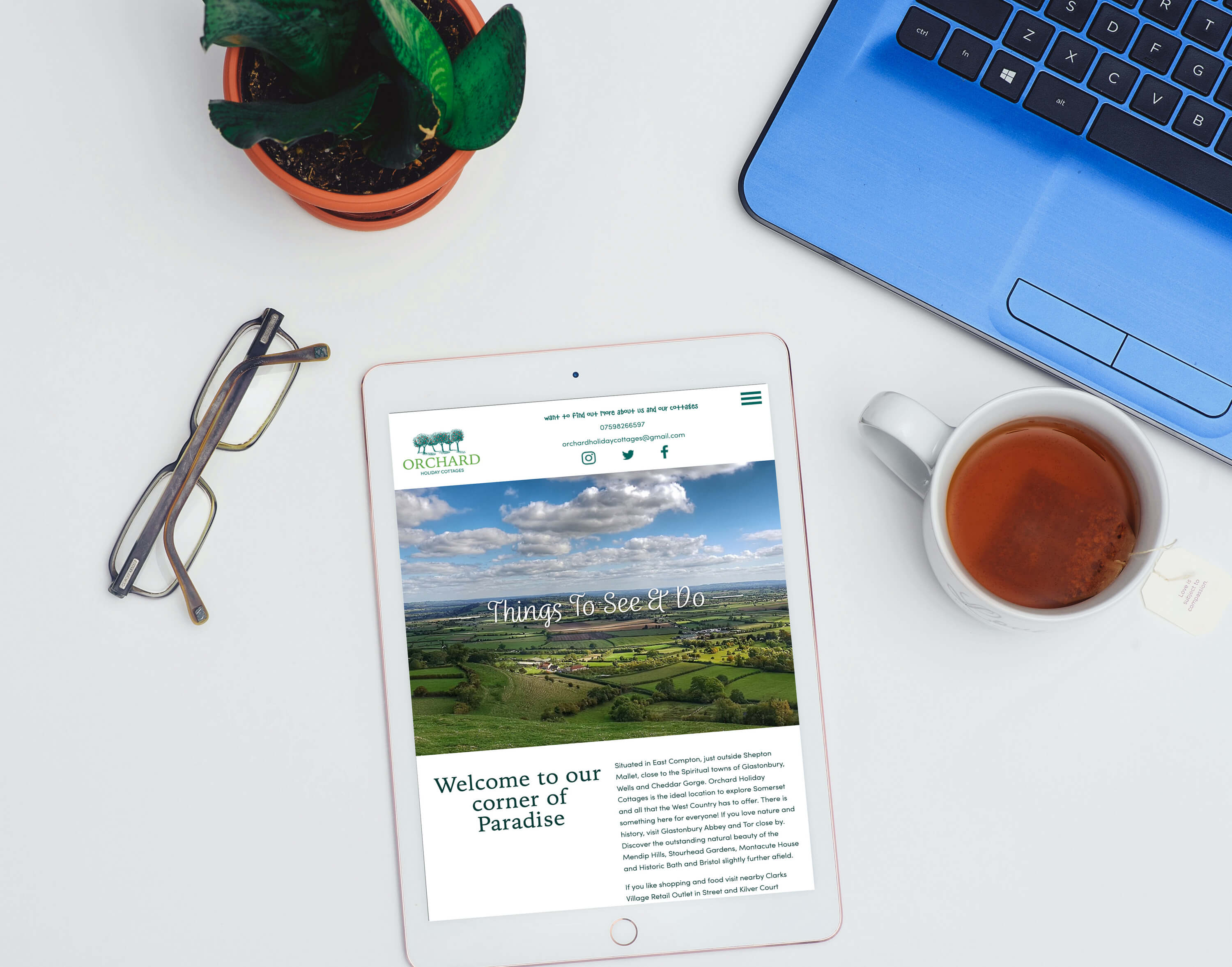 Tablet displaying a bespoke website for a rural tourism business, surrounded by workspace items including laptop and tea.