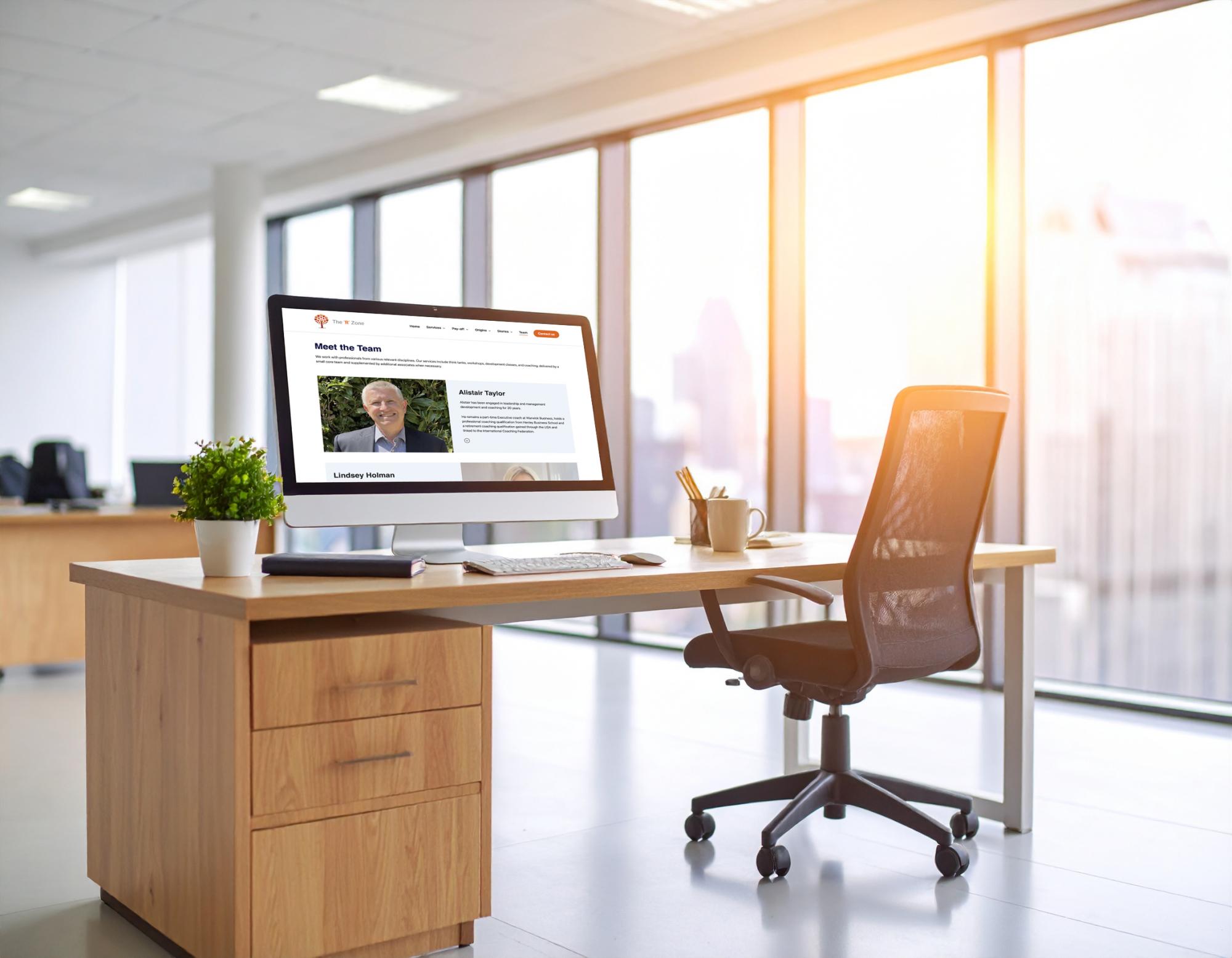 Modern office desk displaying Motley Digital website on monitor, with plant and stationery.